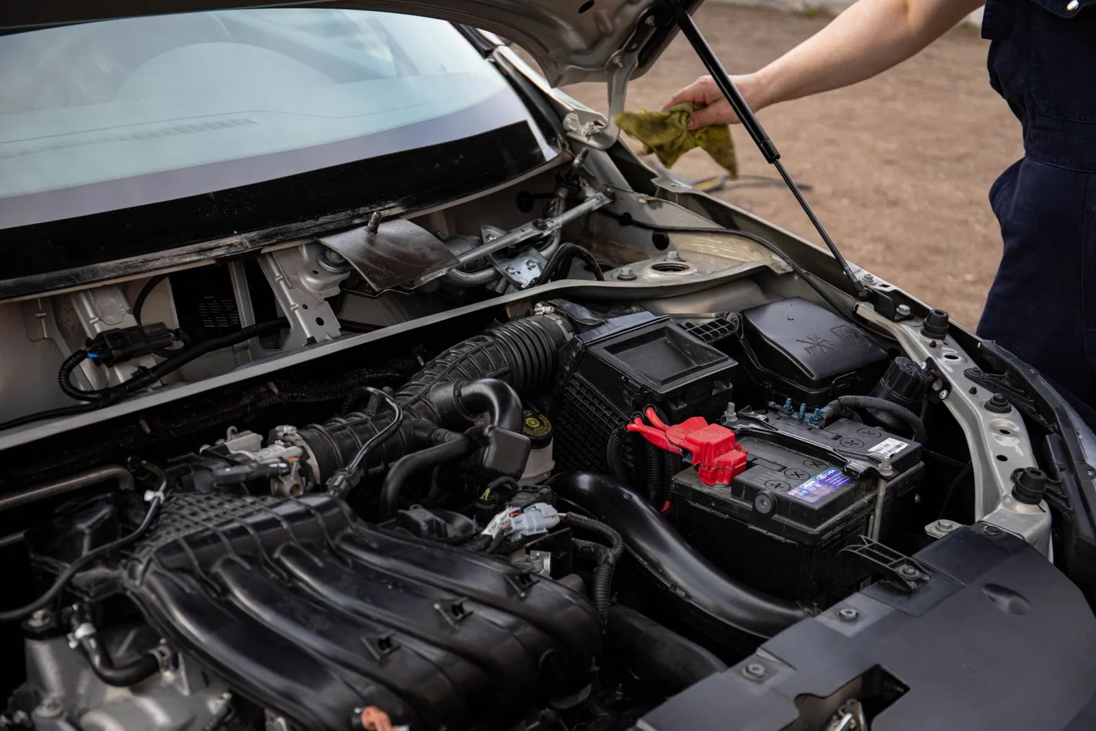 Technician inspecting the battery and engine bay of a car