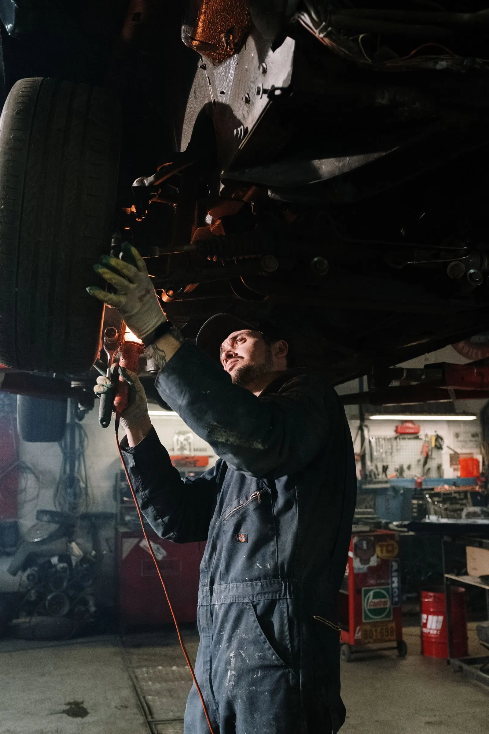 Technician repairing the underside of a vehicle in a garage