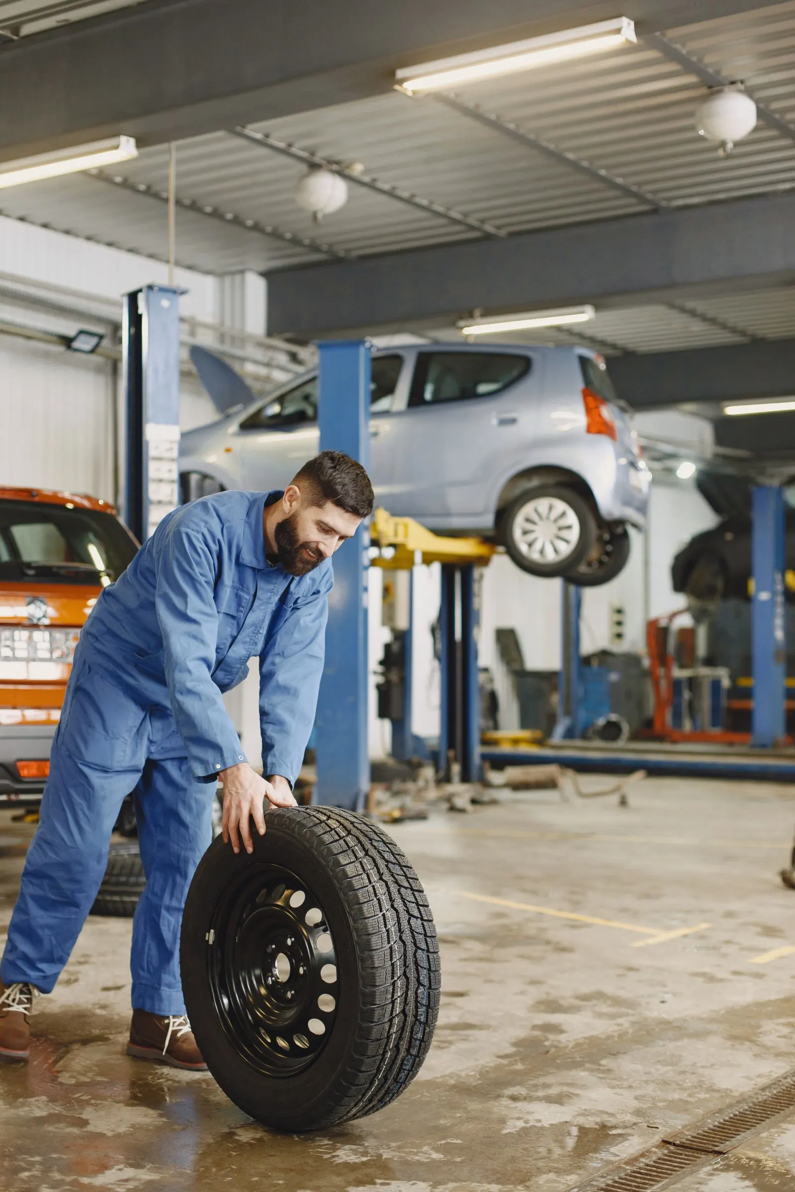 Technician handling a car tire in a service bay